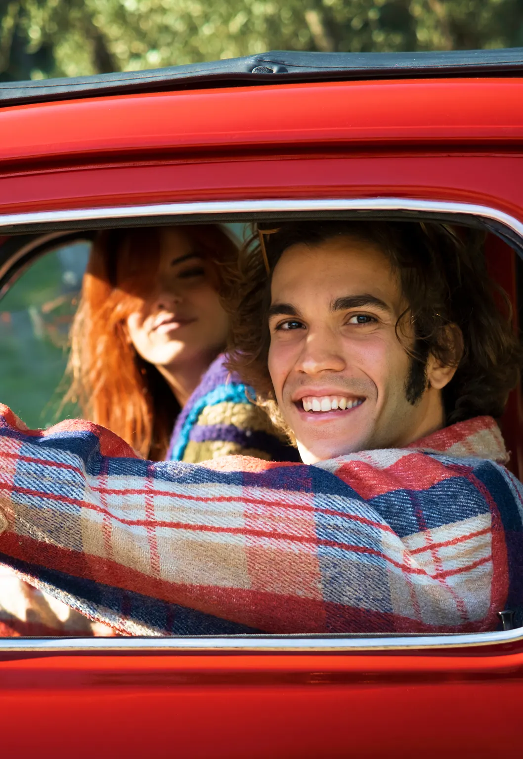 Close up image of a smiling couple driving their classic car